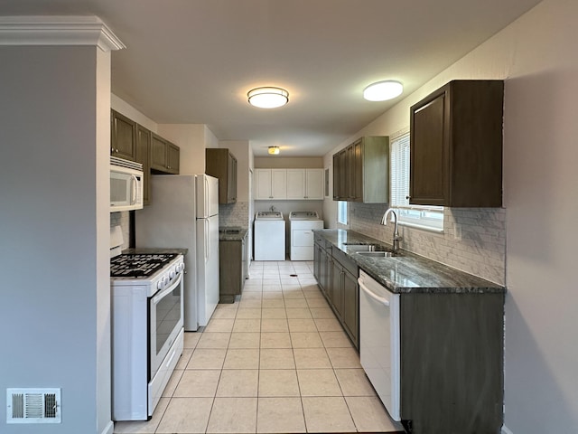 kitchen featuring light tile patterned floors, washing machine and dryer, white appliances, a sink, and visible vents