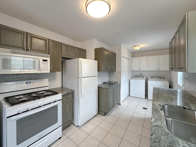 kitchen featuring light tile patterned floors, backsplash, a sink, washer and dryer, and white appliances