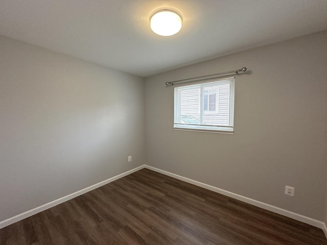 empty room with dark wood-type flooring and baseboards