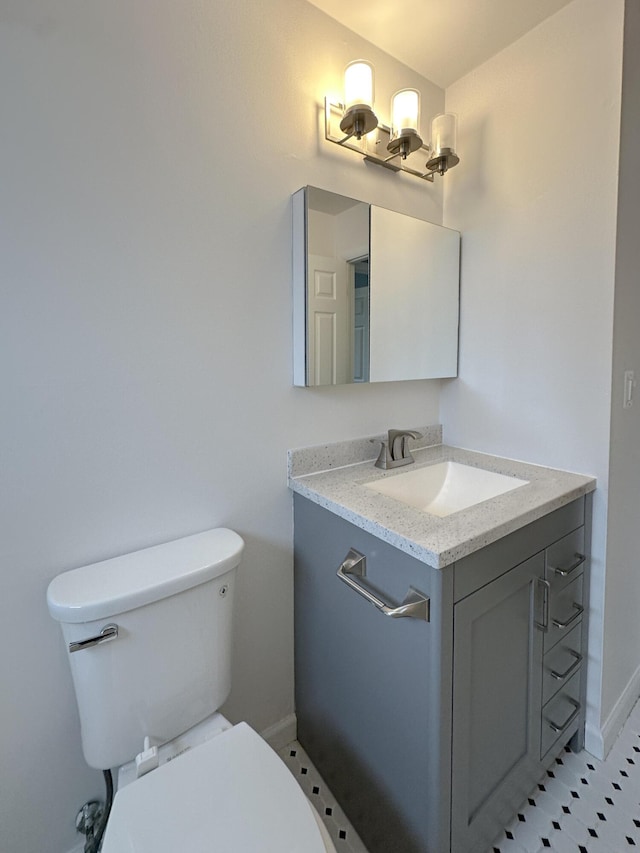 bathroom featuring toilet, baseboards, and vanity