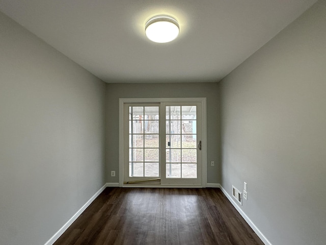 spare room featuring baseboards, visible vents, and dark wood finished floors