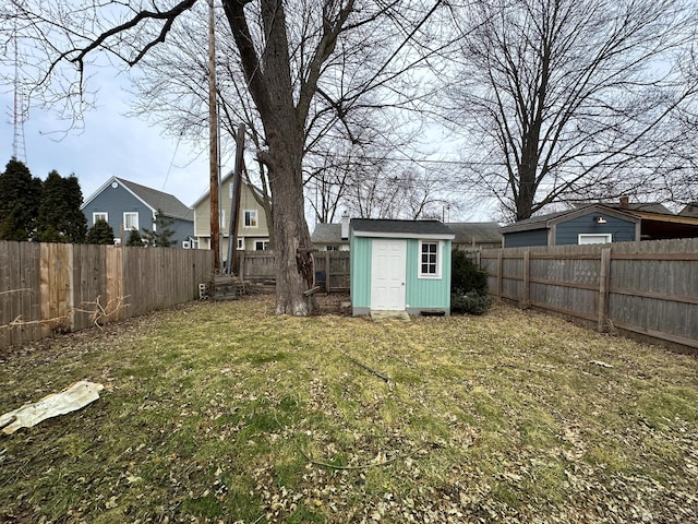 view of yard featuring a storage shed, a fenced backyard, and an outdoor structure