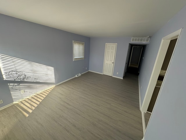 unfurnished room with baseboards, visible vents, and wood finished floors