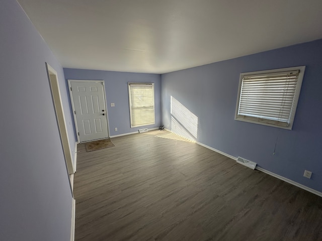 interior space with dark wood-type flooring, visible vents, and baseboards