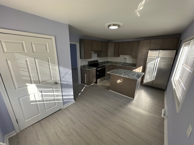 kitchen with dark brown cabinets, appliances with stainless steel finishes, light wood-type flooring, and a sink