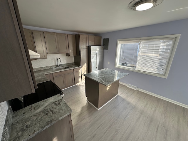 kitchen with visible vents, light wood-style floors, freestanding refrigerator, a sink, and baseboards