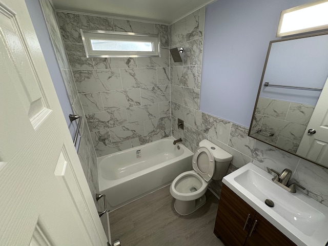 full bathroom featuring toilet, shower / bath combination, wood finished floors, vanity, and tile walls