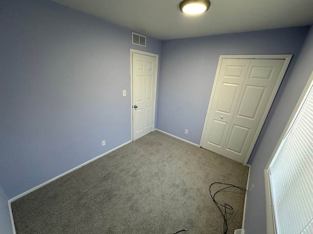 unfurnished bedroom with a closet, carpet, visible vents, and baseboards