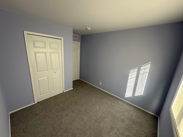 unfurnished bedroom with carpet, a closet, visible vents, and baseboards