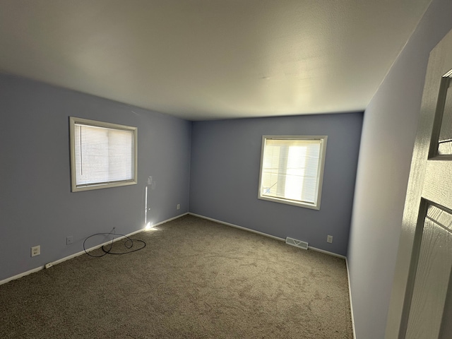 spare room featuring baseboards, visible vents, and carpet flooring