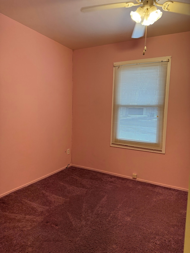 unfurnished room featuring a ceiling fan, dark carpet, and baseboards