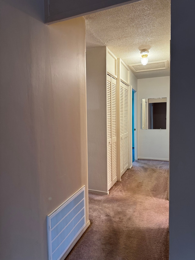 hallway featuring carpet and a textured ceiling