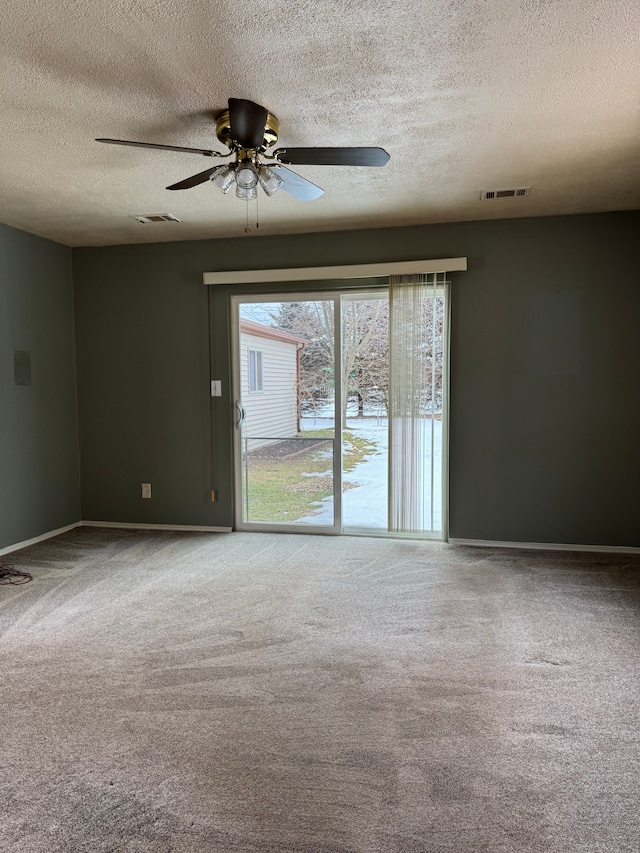 carpeted spare room with baseboards, a textured ceiling, visible vents, and a ceiling fan