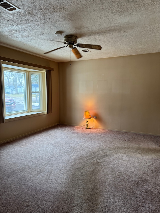 unfurnished room featuring ceiling fan, a textured ceiling, carpet, and visible vents