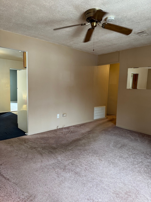 carpeted spare room with a ceiling fan, visible vents, and a textured ceiling