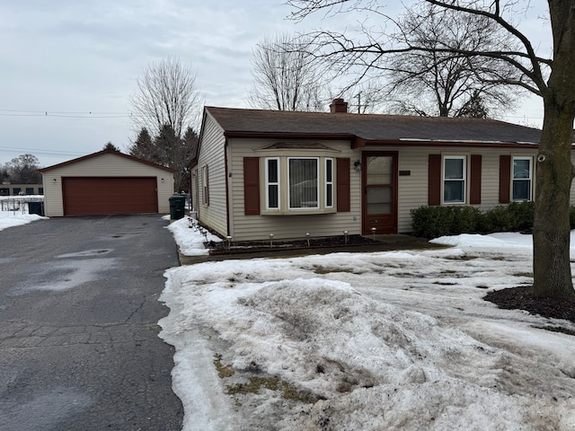 view of front of property featuring a garage, an outdoor structure, a chimney, and a shingled roof