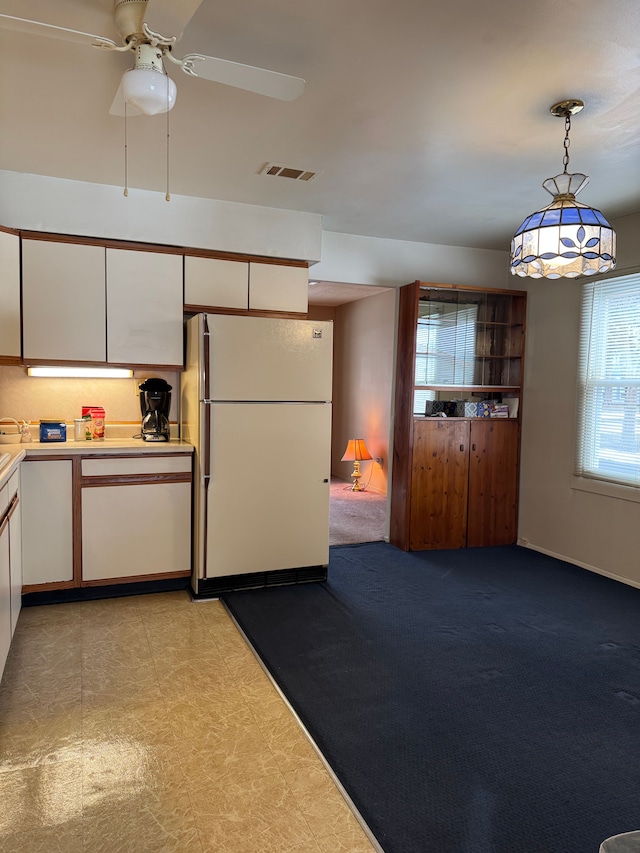 kitchen featuring visible vents, light countertops, freestanding refrigerator, and white cabinetry