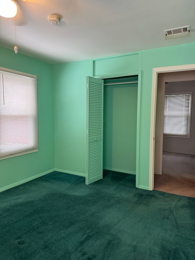 unfurnished bedroom with a closet, carpet, visible vents, and baseboards