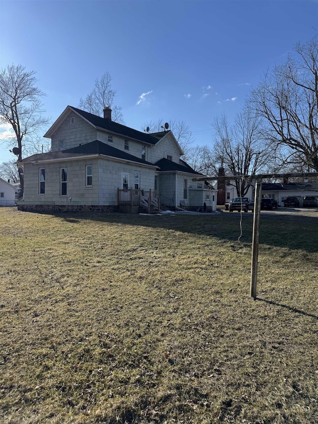 back of house featuring a lawn and a chimney
