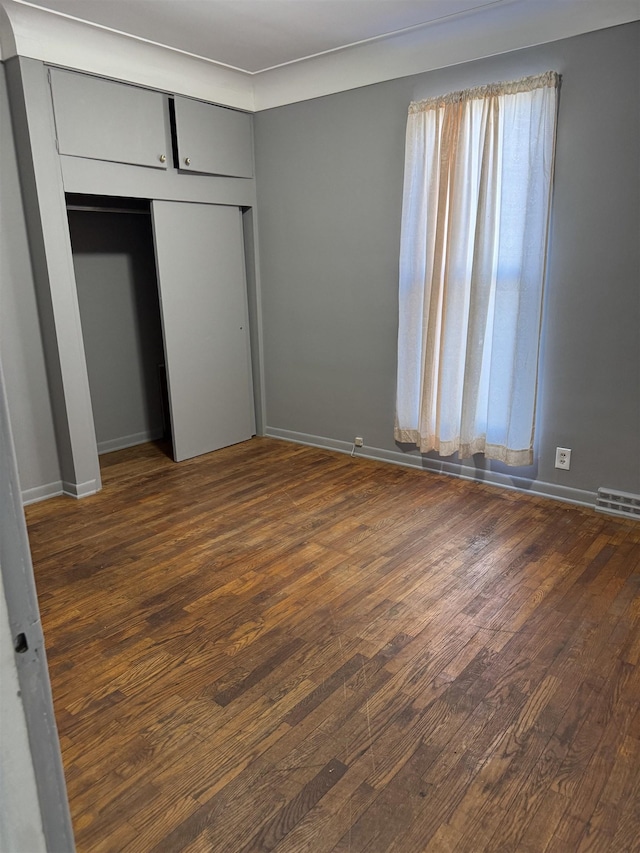 unfurnished bedroom with baseboards, visible vents, and dark wood-style flooring