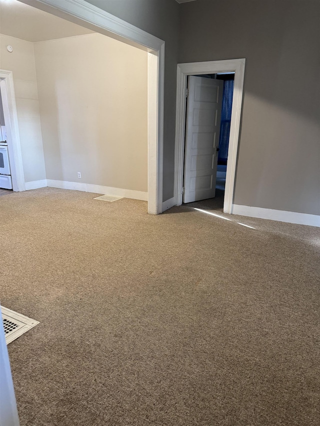 unfurnished room with carpet floors, visible vents, and baseboards