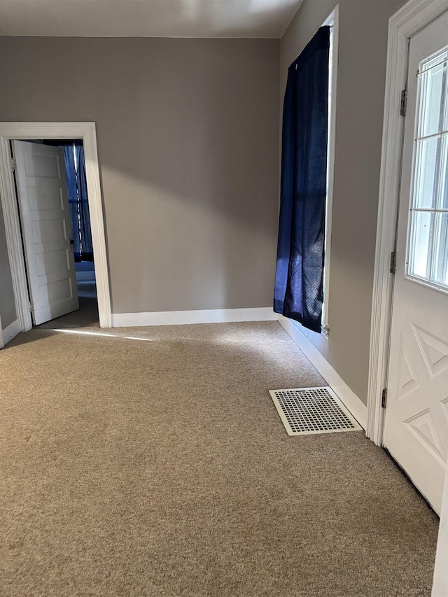 carpeted spare room featuring visible vents and baseboards