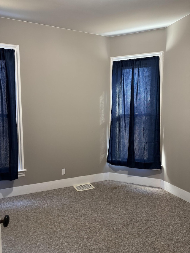 carpeted empty room featuring visible vents and baseboards