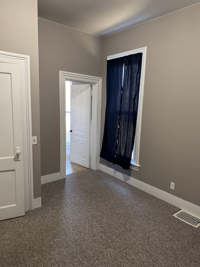 carpeted empty room featuring visible vents and baseboards