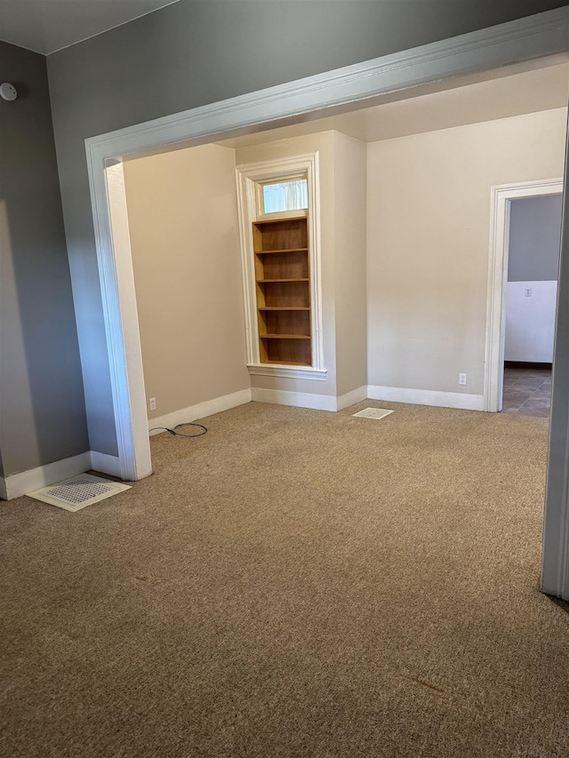 carpeted empty room with visible vents and baseboards