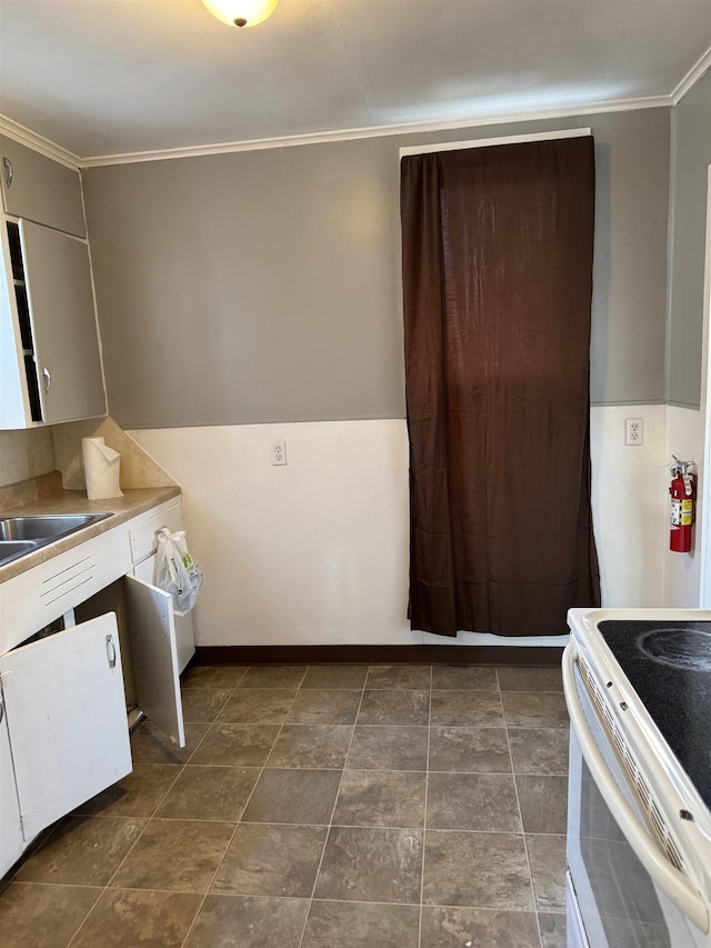 kitchen with ornamental molding, white range with electric stovetop, a sink, and baseboards