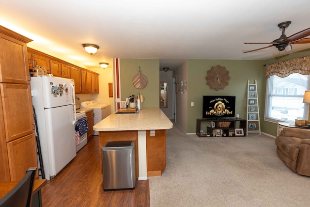 kitchen with a sink, open floor plan, freestanding refrigerator, brown cabinetry, and washing machine and clothes dryer