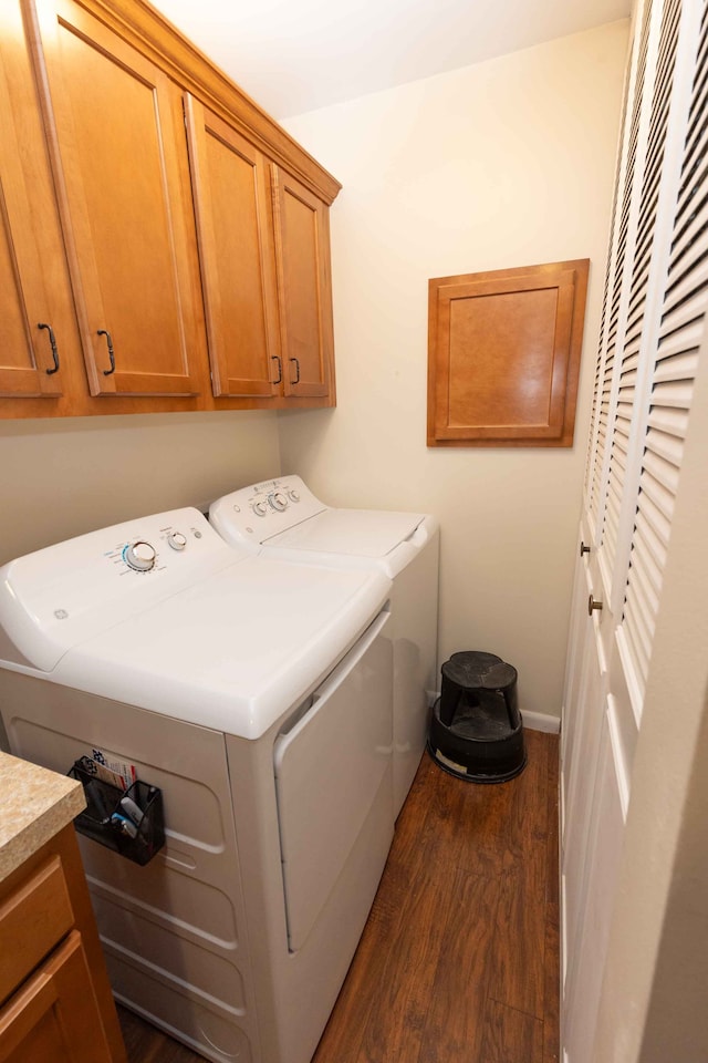 washroom with dark wood-type flooring, cabinet space, washer and clothes dryer, and baseboards