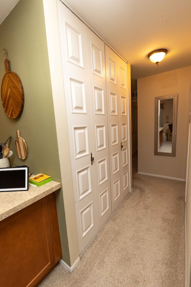 hall featuring baseboards and light colored carpet