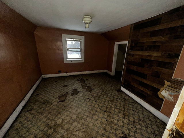 additional living space featuring baseboards and vaulted ceiling