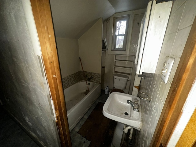 bathroom featuring a tub to relax in, a sink, vaulted ceiling, and toilet