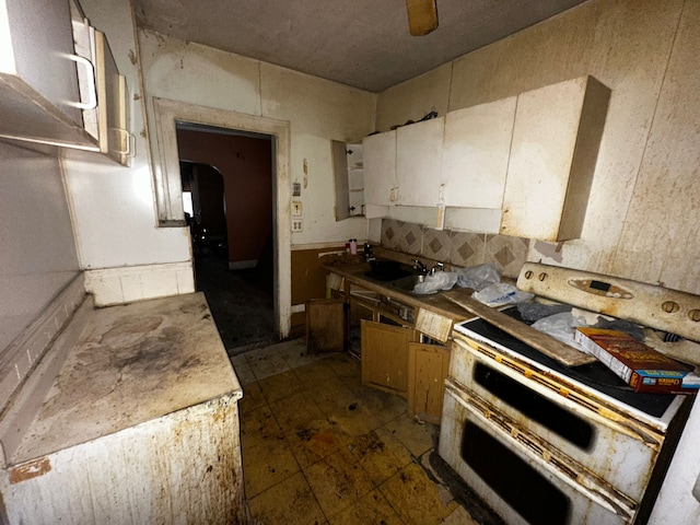 kitchen featuring ceiling fan, a sink, white cabinetry, and double oven range