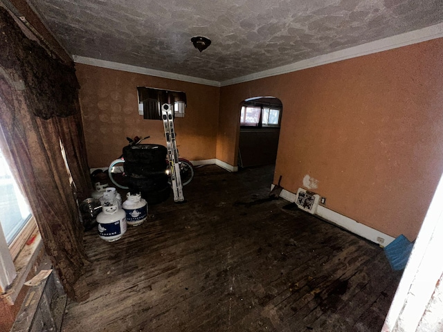 interior space featuring baseboards, arched walkways, wood finished floors, and ornamental molding