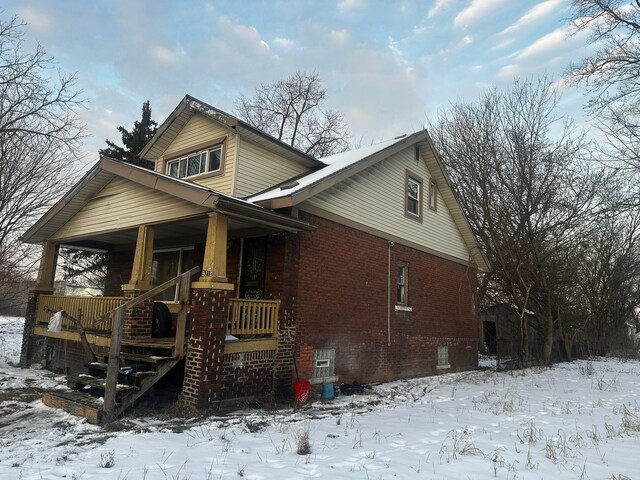 view of front of house with covered porch, stairway, and brick siding