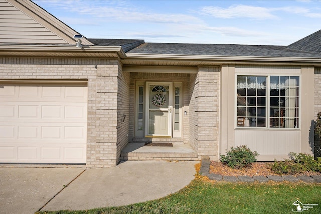 doorway to property featuring an attached garage, brick siding, and roof with shingles