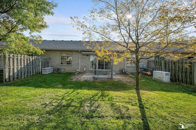 rear view of property featuring a fenced backyard, a lawn, and brick siding