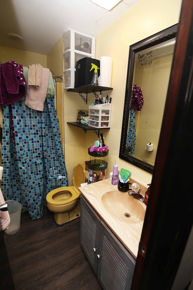 bathroom featuring toilet, curtained shower, wood finished floors, and vanity