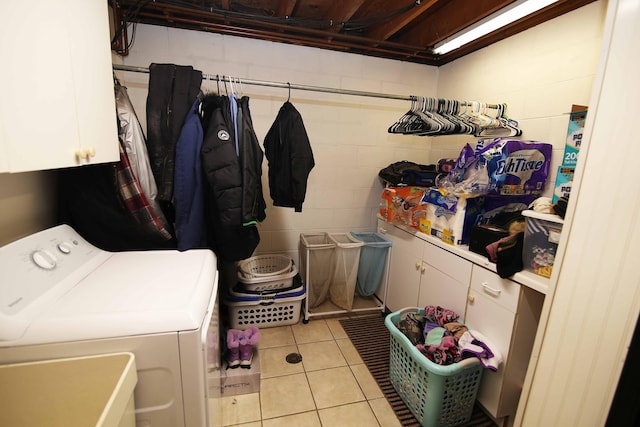 washroom with washer / dryer, concrete block wall, cabinet space, and light tile patterned flooring