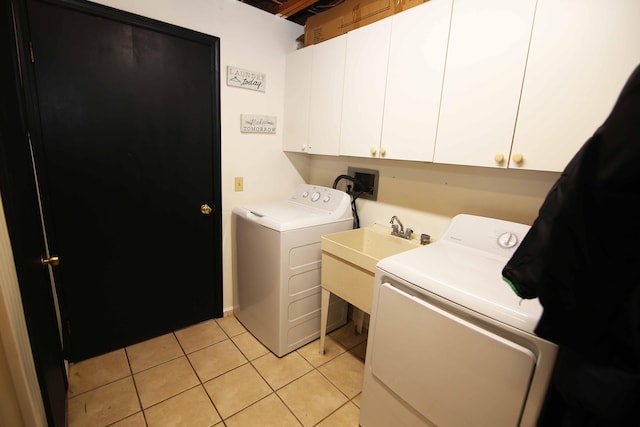 washroom with cabinet space, a sink, washing machine and clothes dryer, and light tile patterned floors