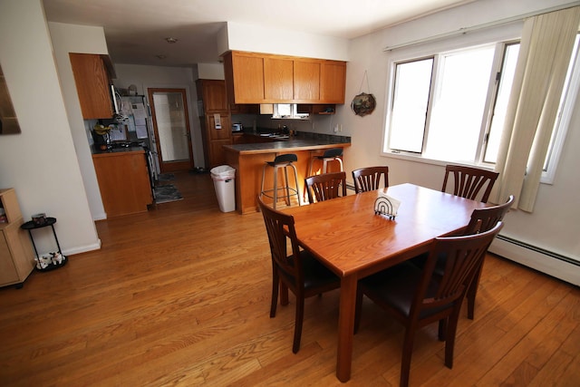 dining area with light wood-type flooring, baseboards, and a baseboard radiator