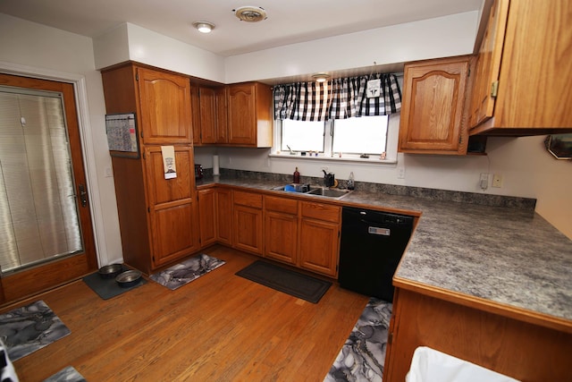 kitchen featuring brown cabinetry, light wood-type flooring, dishwasher, and a sink