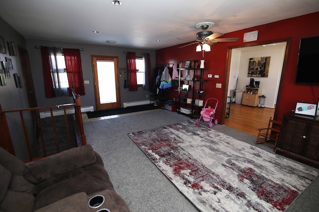 living area featuring a baseboard heating unit, baseboard heating, a ceiling fan, and a healthy amount of sunlight