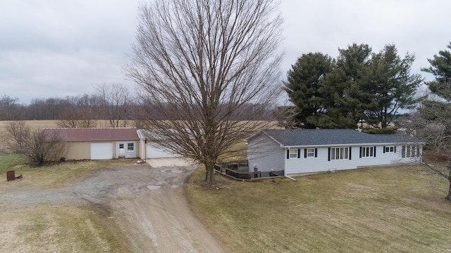 ranch-style home with a front yard, an outdoor structure, and dirt driveway