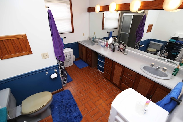 bathroom with double vanity, a stall shower, brick patterned floor, and a sink