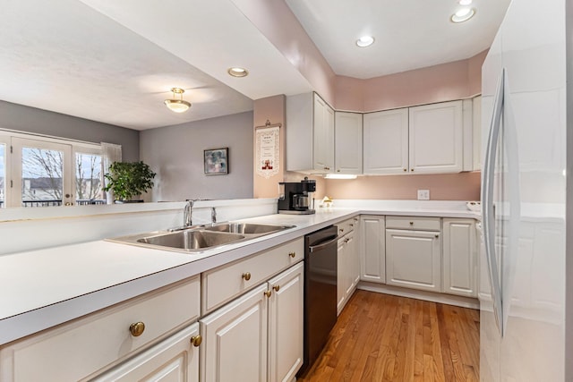 kitchen with light countertops, light wood-style floors, freestanding refrigerator, a sink, and dishwasher