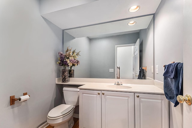 half bath featuring recessed lighting, vanity, and toilet